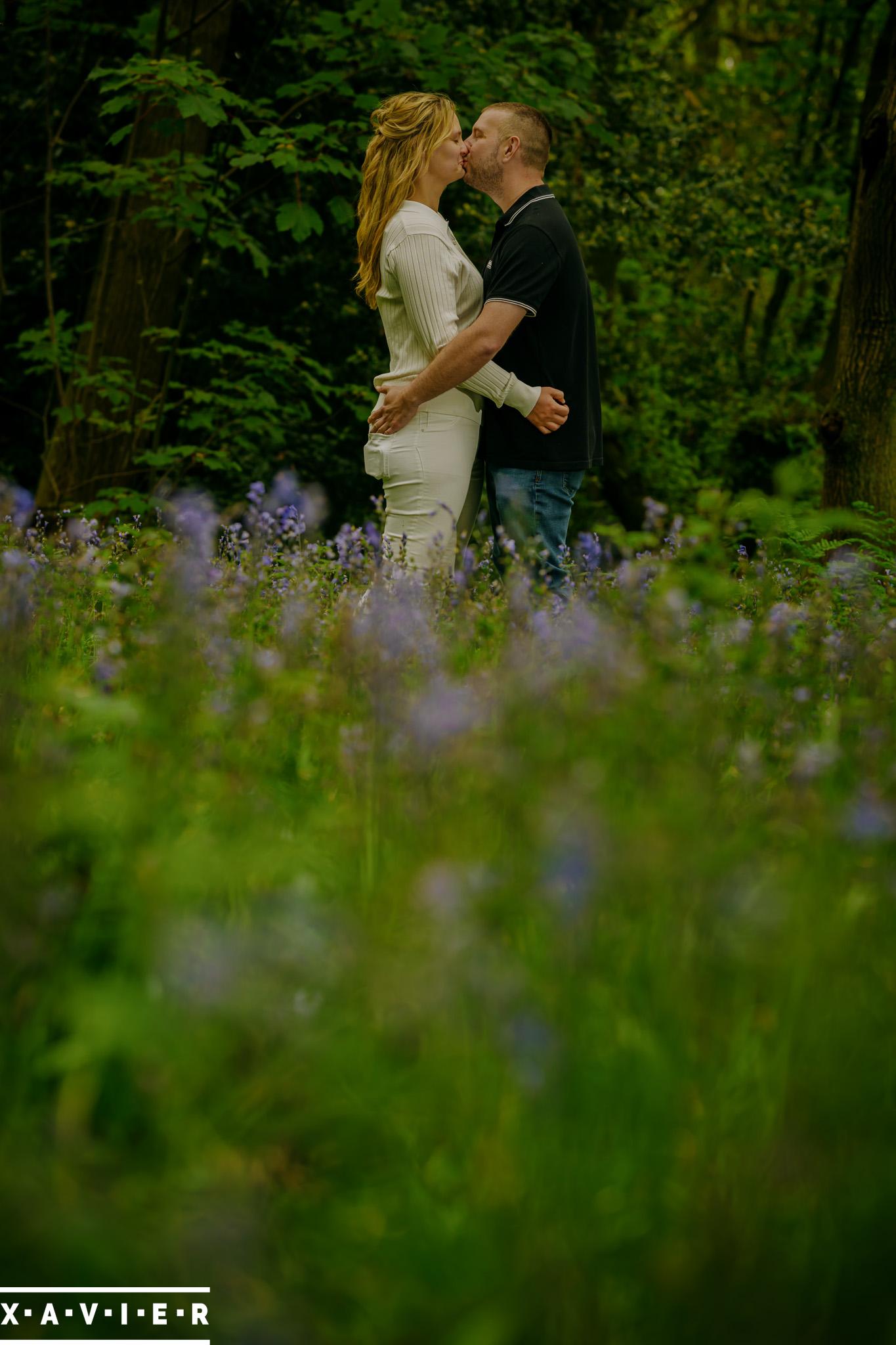 photography engagement session with couple standing in bluebell wood