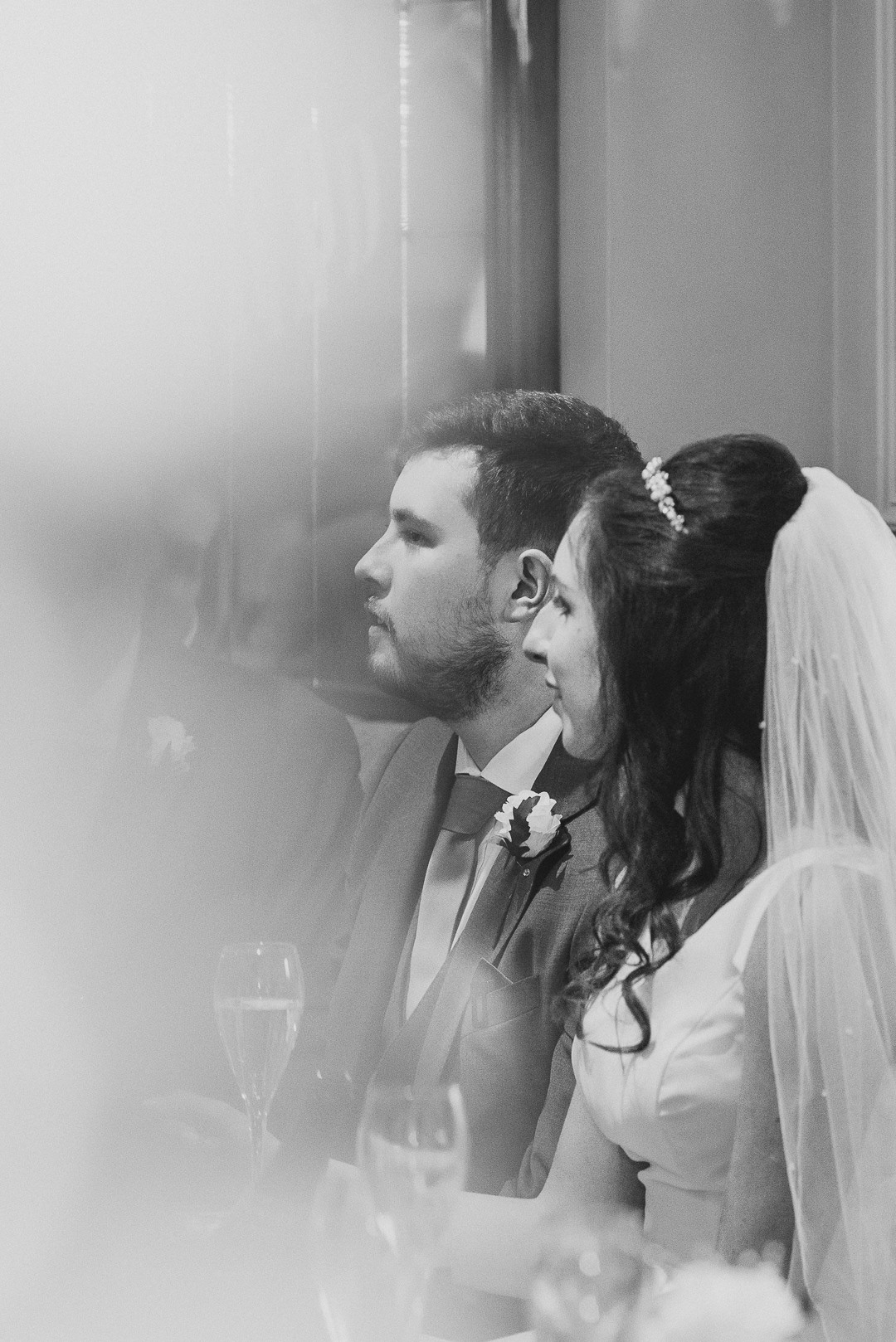 black and white photo of the bride and groom looking at someone out of the frame