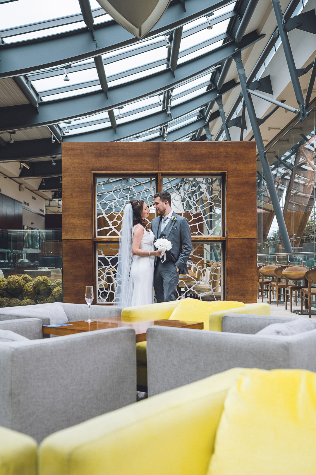 Zoomed photo of the bride and groom stand in front of a wooden square in the mercure hotel