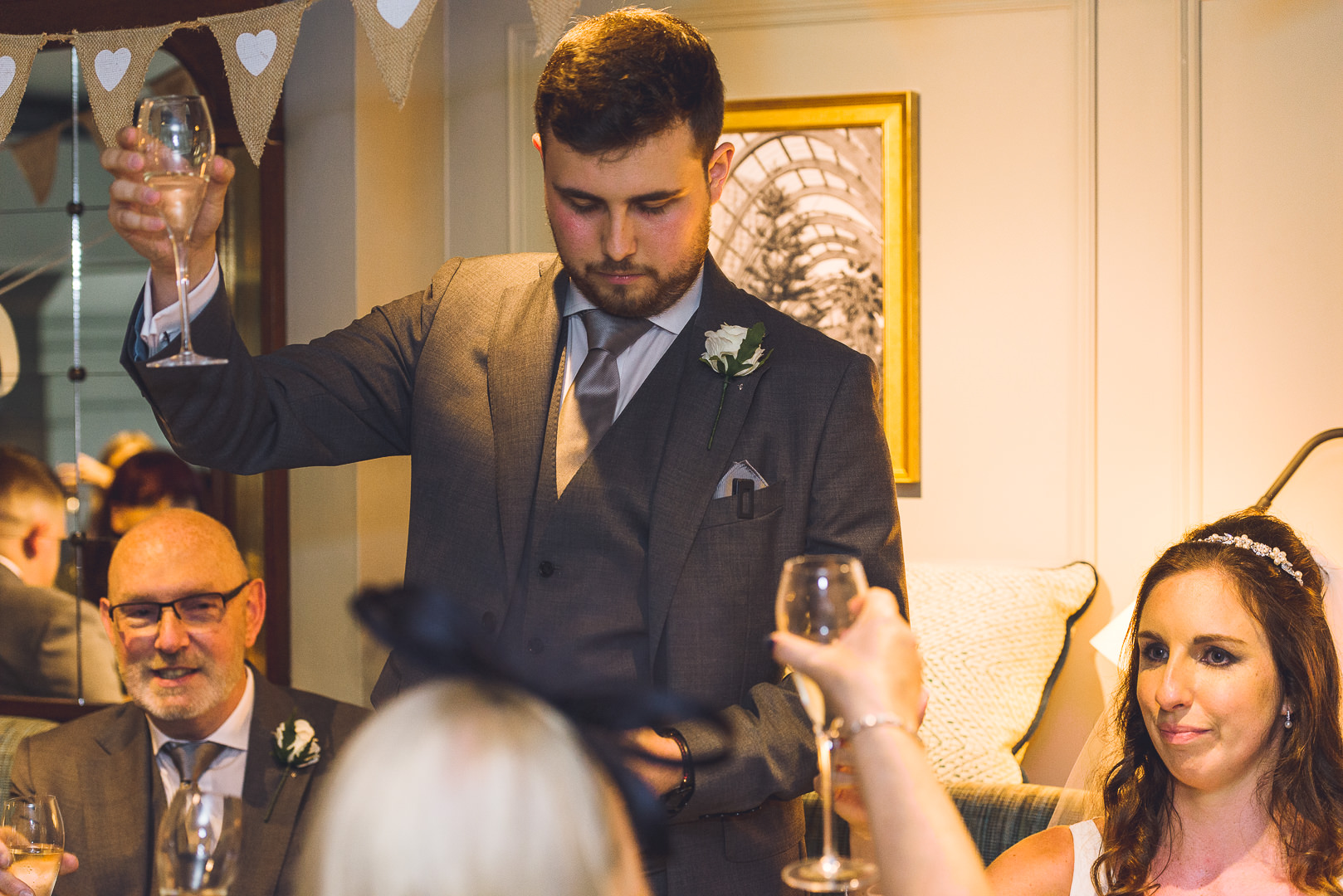 The groom raises his glass to signal a toast