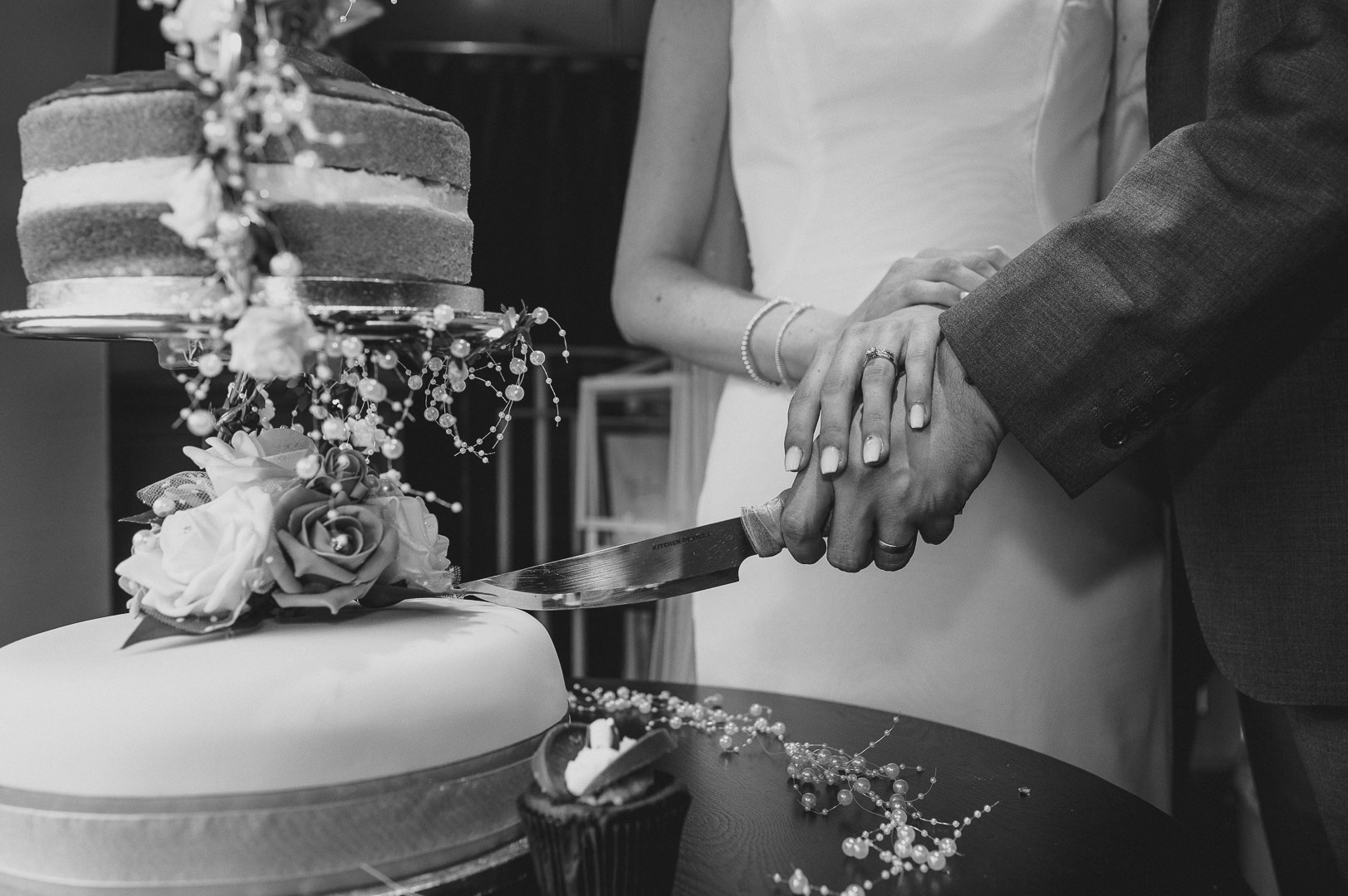 black and white photo of the bride and groom cutting the cake
