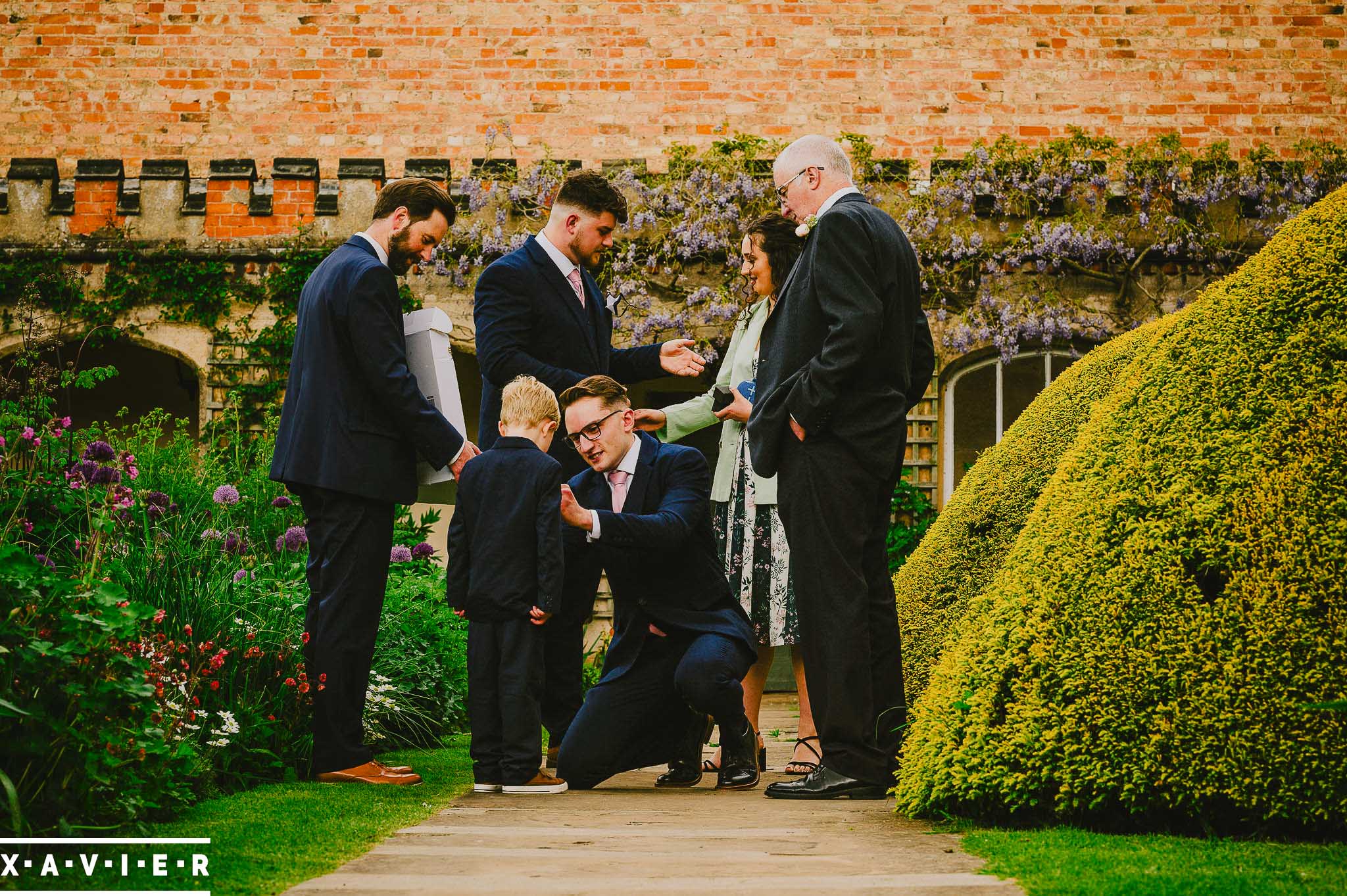 groom puts the button-hole flower on a paige boy