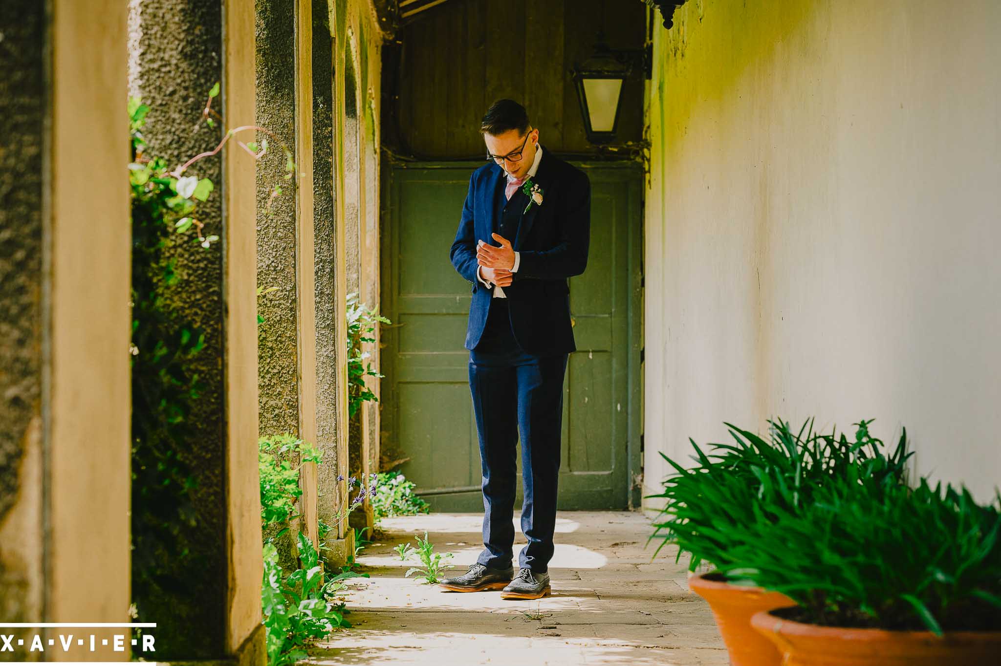 groom adjusts his cuffs in the courtyard
