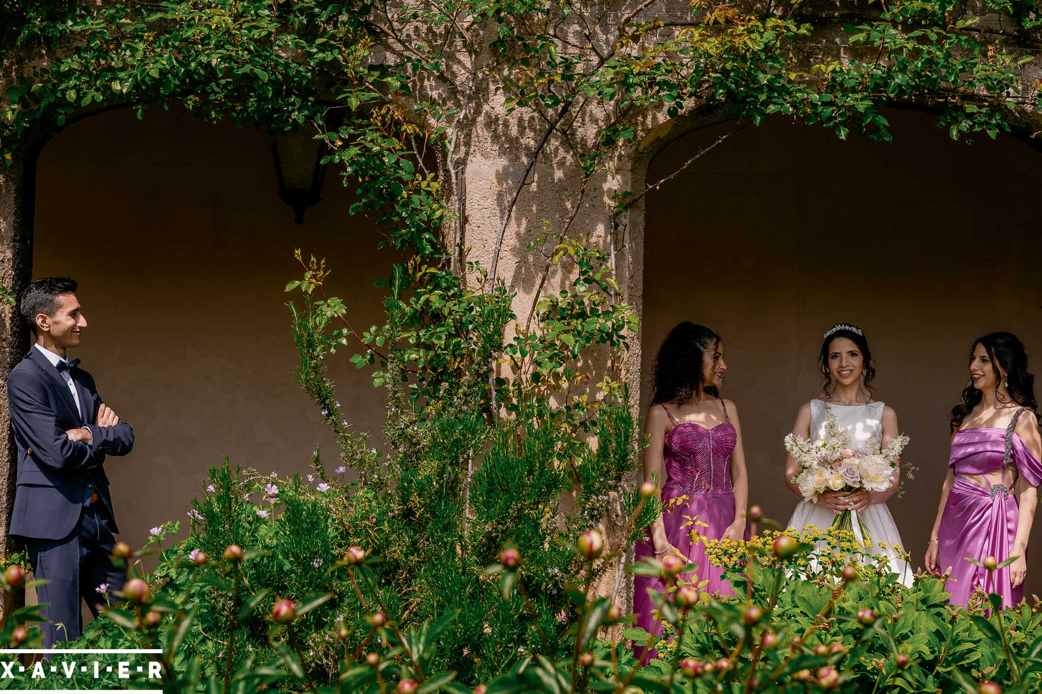 groom and bridesmaids stand in the courtyard