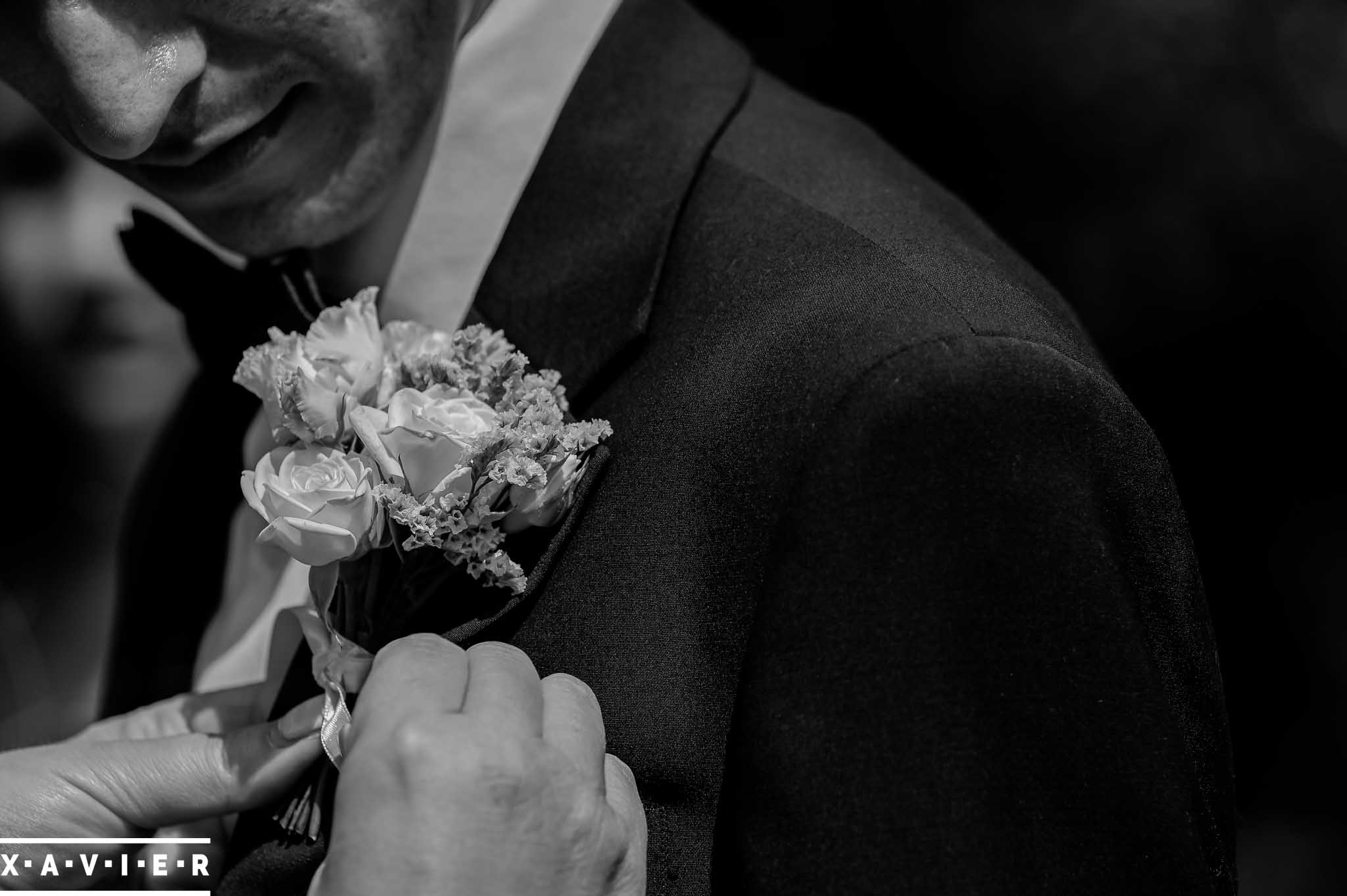 groom having his buttonhole flower fastened onto his lapel