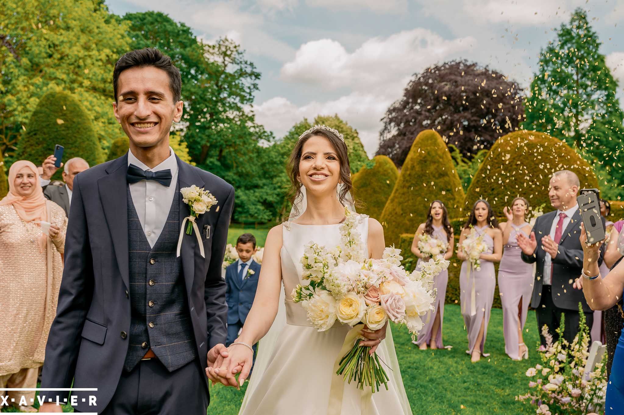 Bride and groom walk beneath the confetti