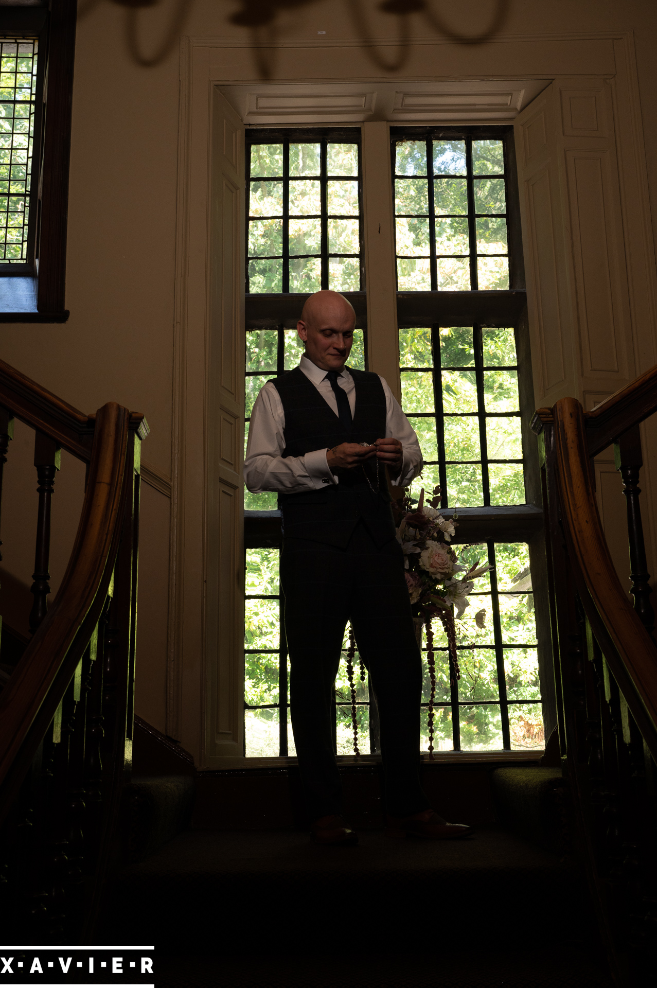 groom stands on the stairs and is checking the time