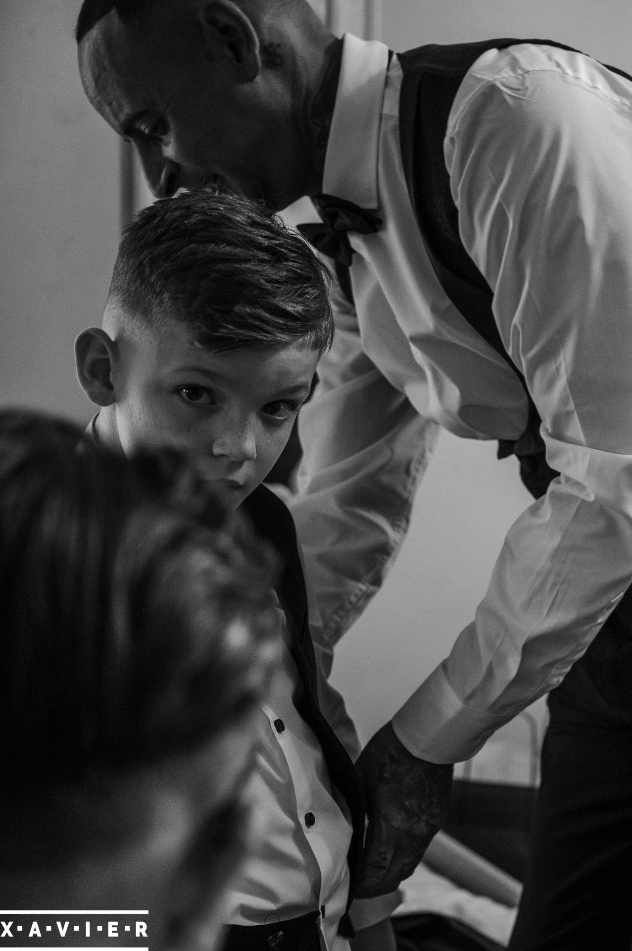 candid image of page boy being helped into his suit by the groom