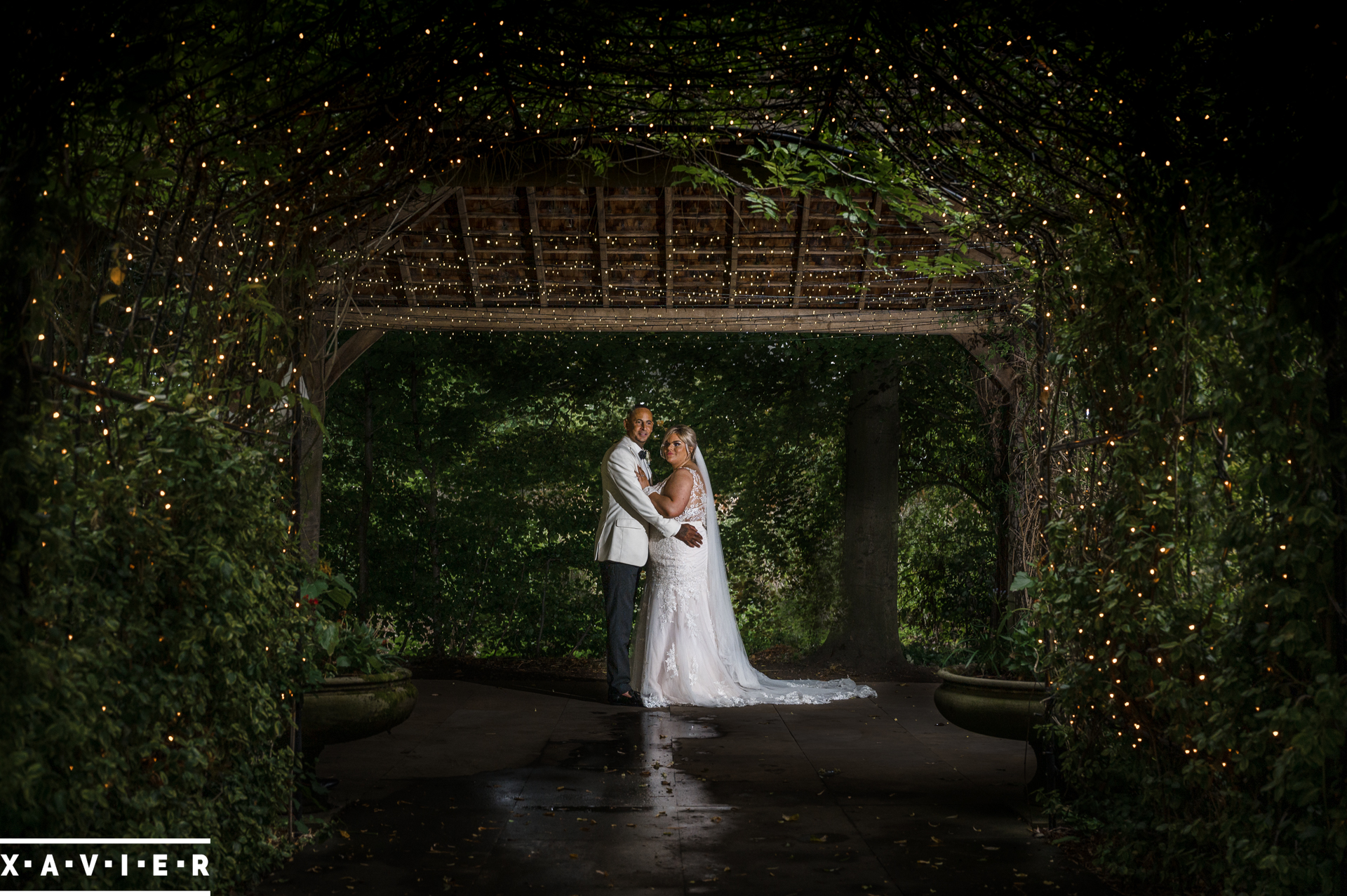 bride and groom hold each other under the garden pergoda