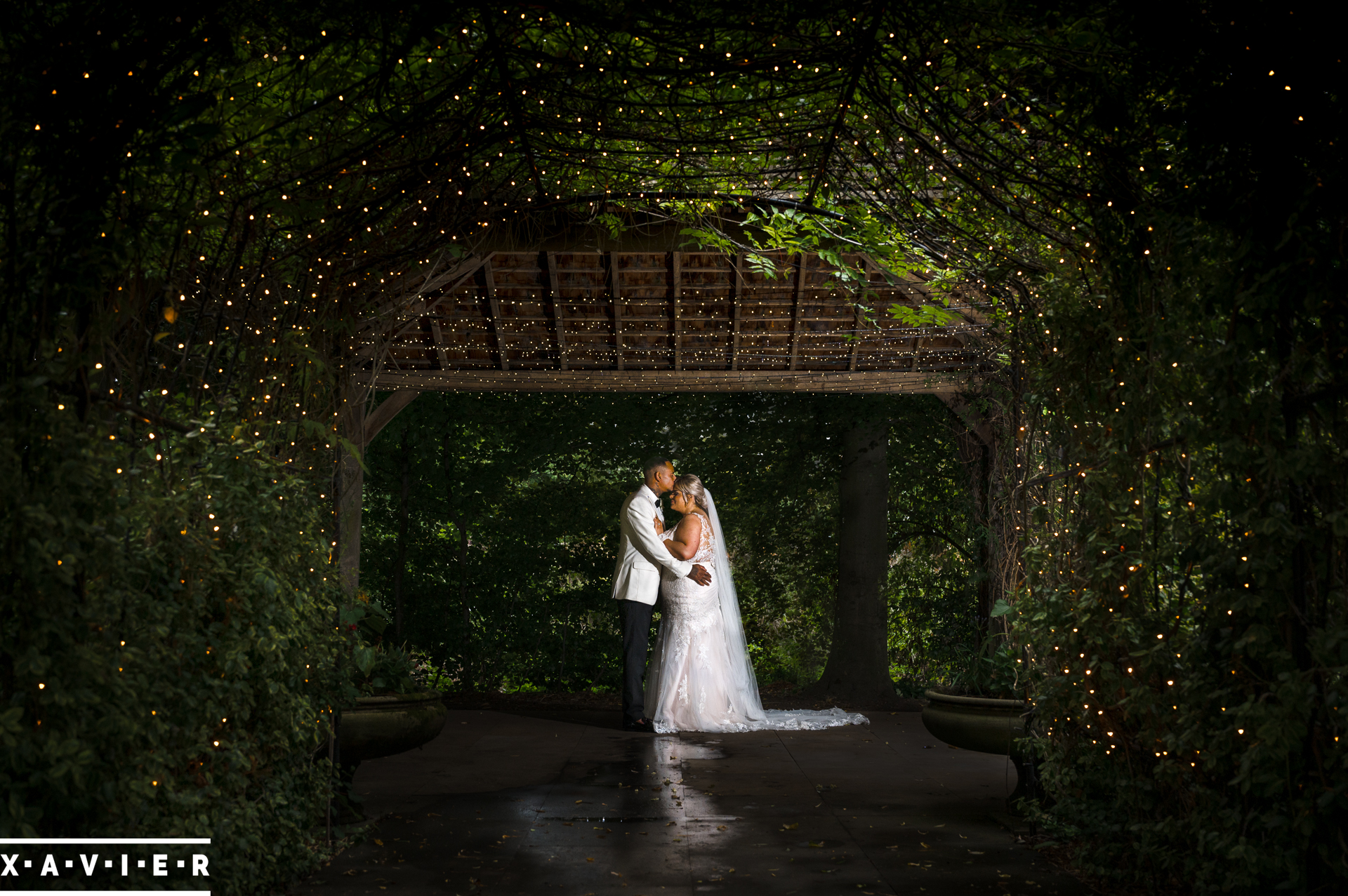 groom kisses the bride under the garden tunnel