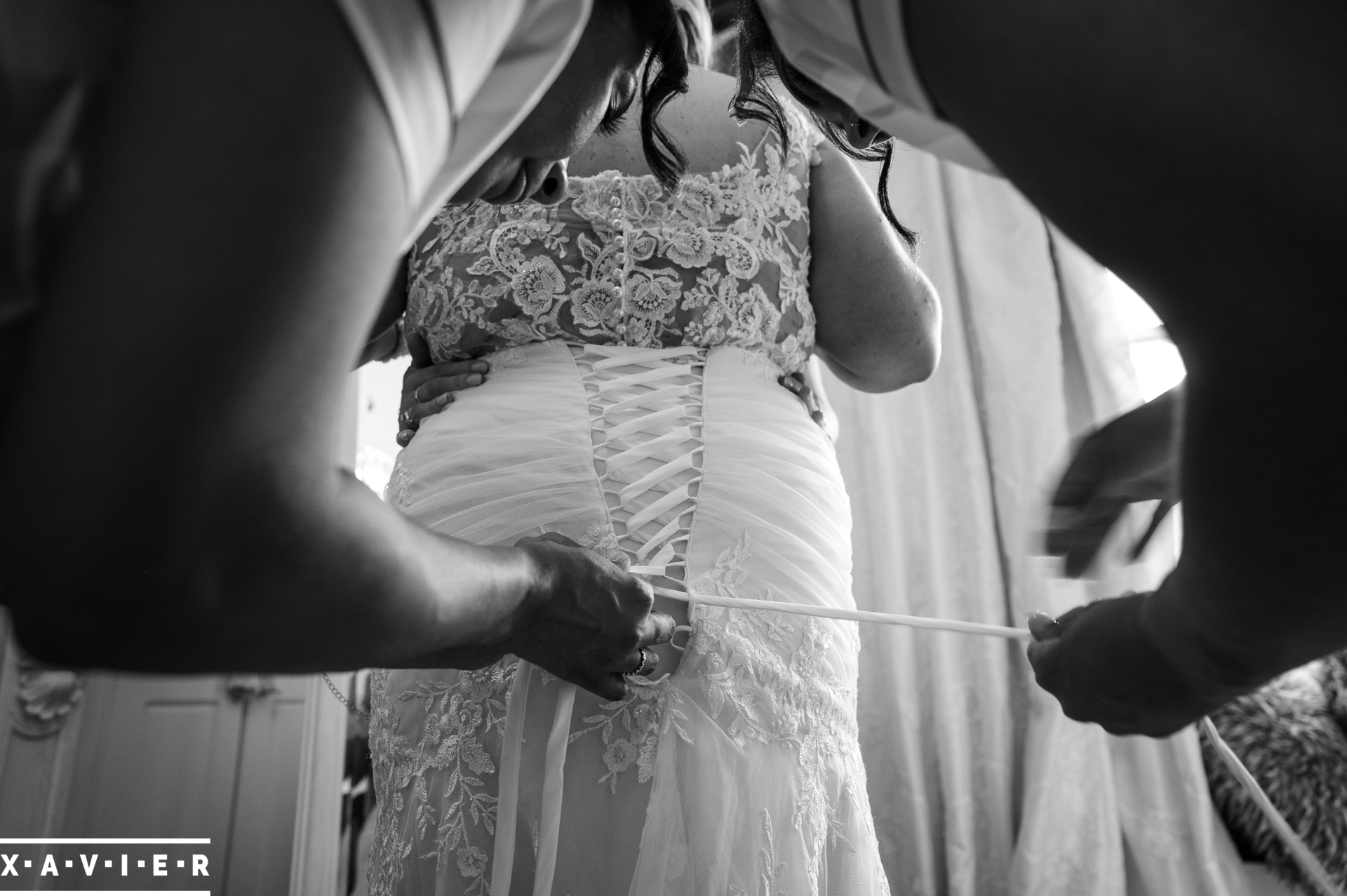 bridesmaids are fastening the brides dress