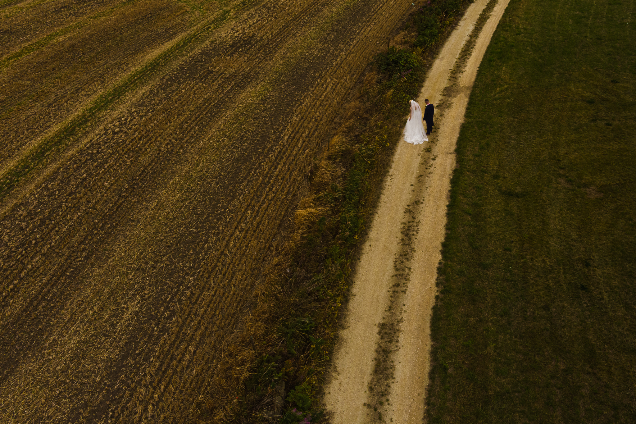 drone photo of bride and groom walking in the fields