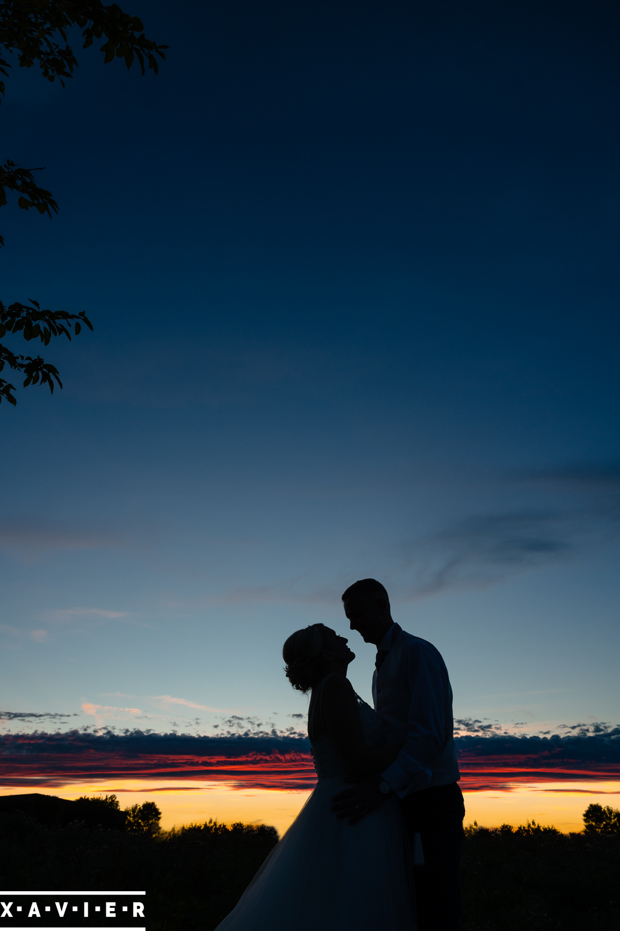 silhouette of bride and grom against a colourful sky