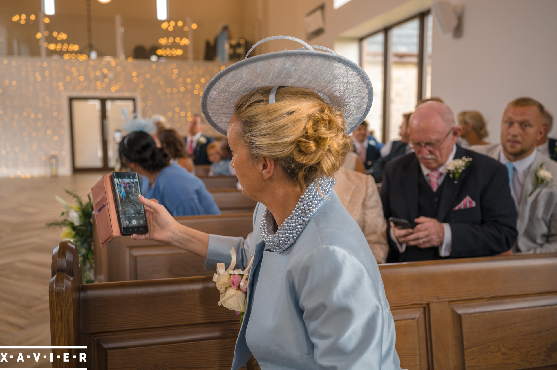 guest is holding her phone to take photos of the bride