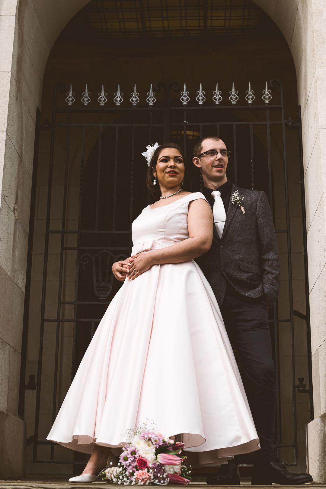 the camera is looking up at the couple as they stand in front of the town hall