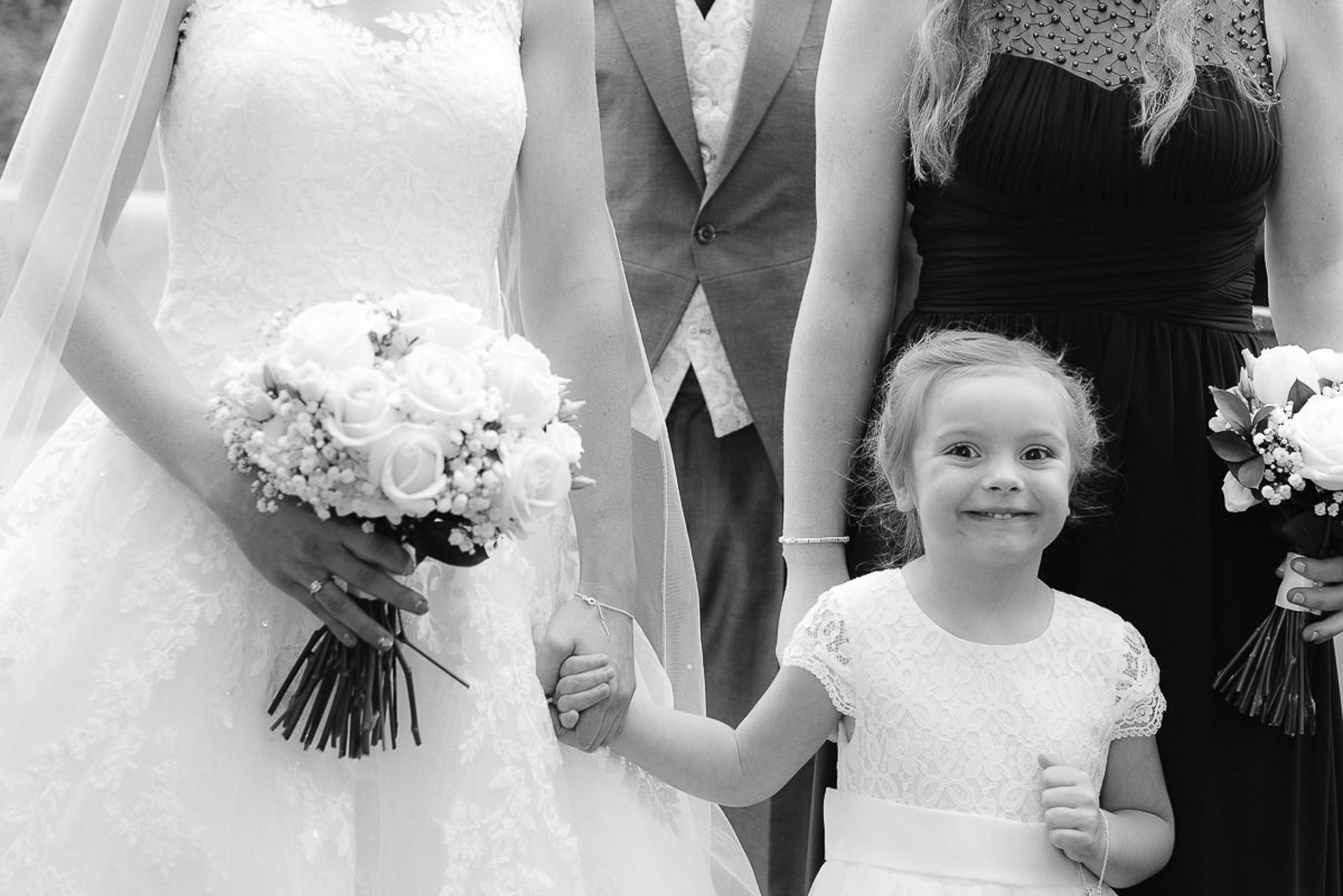 flowergirl walks with bride and bridesmaids, she smiles at the camera