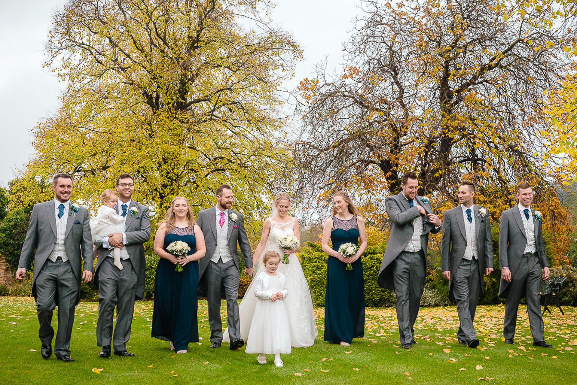 bride and groom walk in the grounds with groomsmen, bridesmaids and flowergirl
