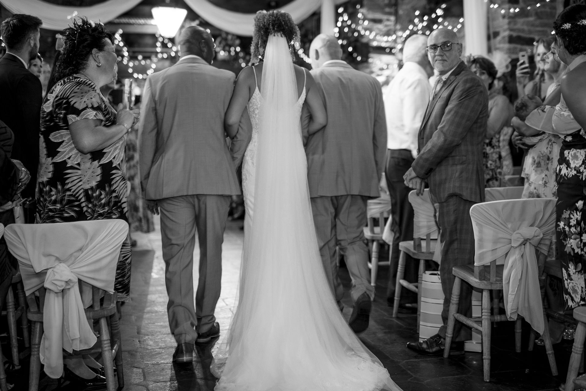 the bride is led down the aisle by her father and step father