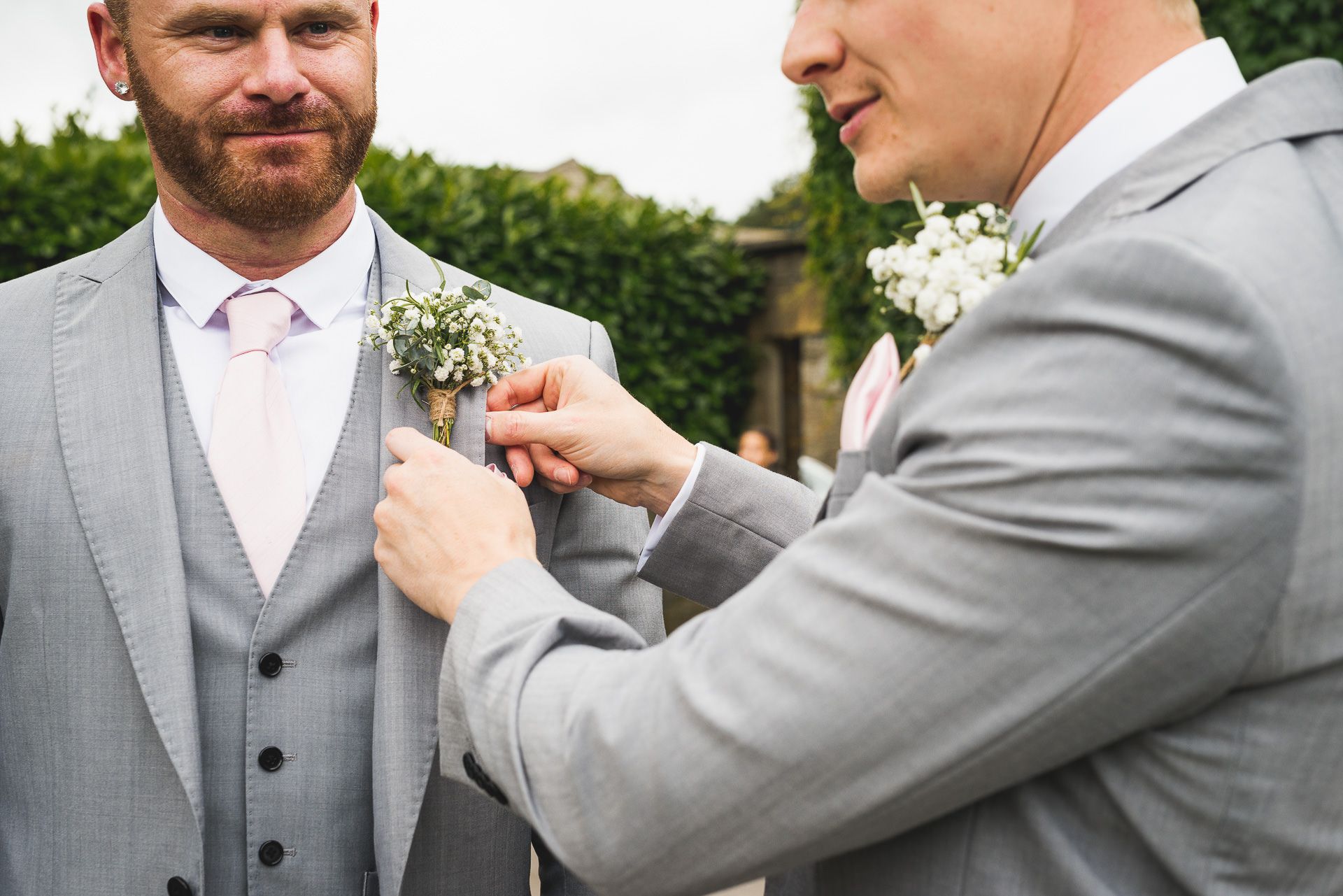 the best man attaches the groom's buttonhole flower