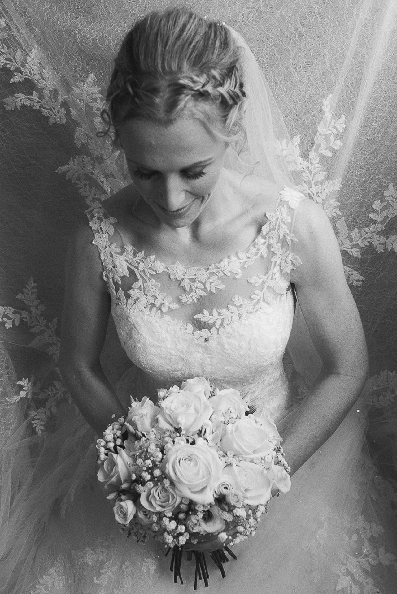 black and white photo of bride kneeling with flowers in her wedding dress