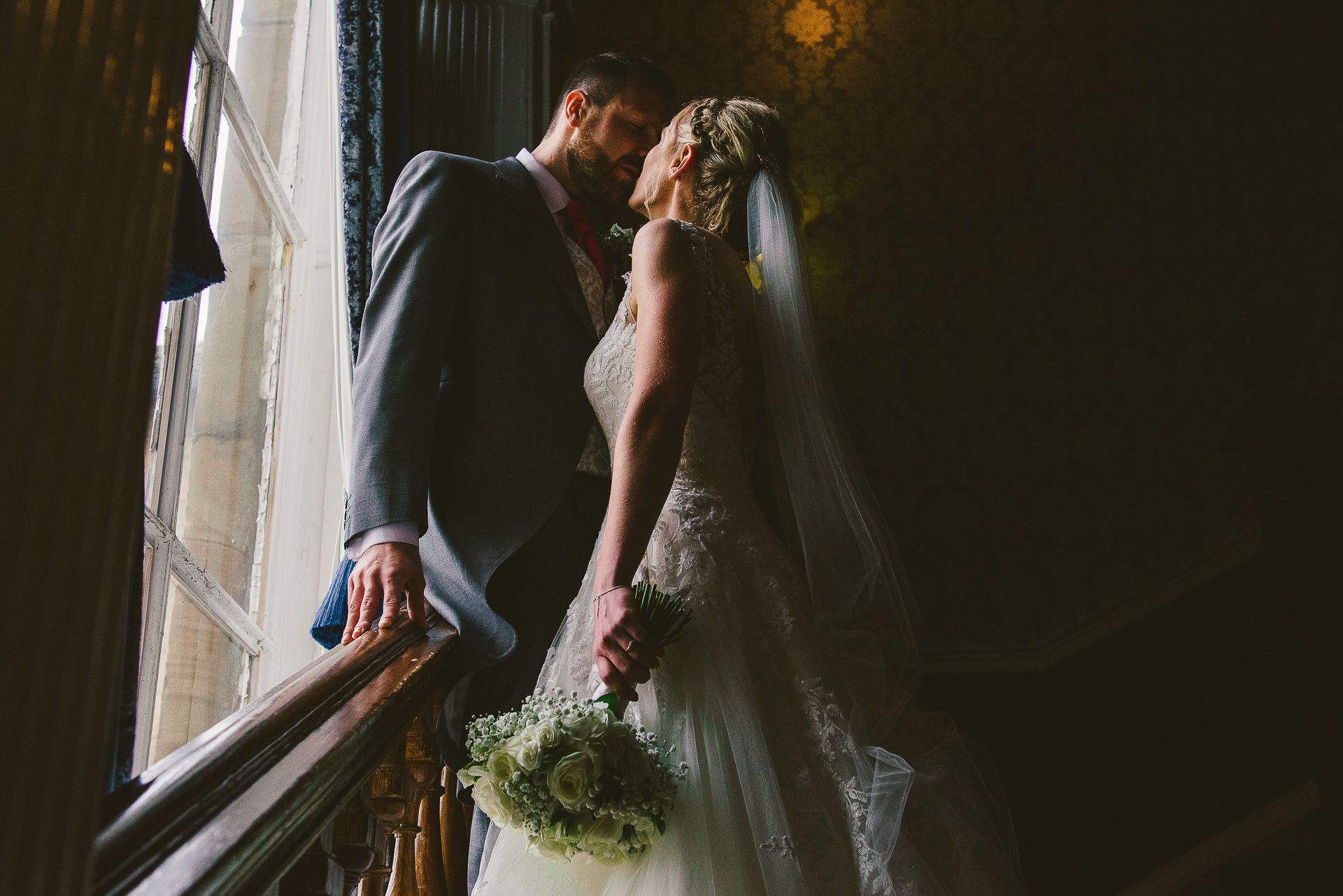 bride and groom share an intimate moment by the window