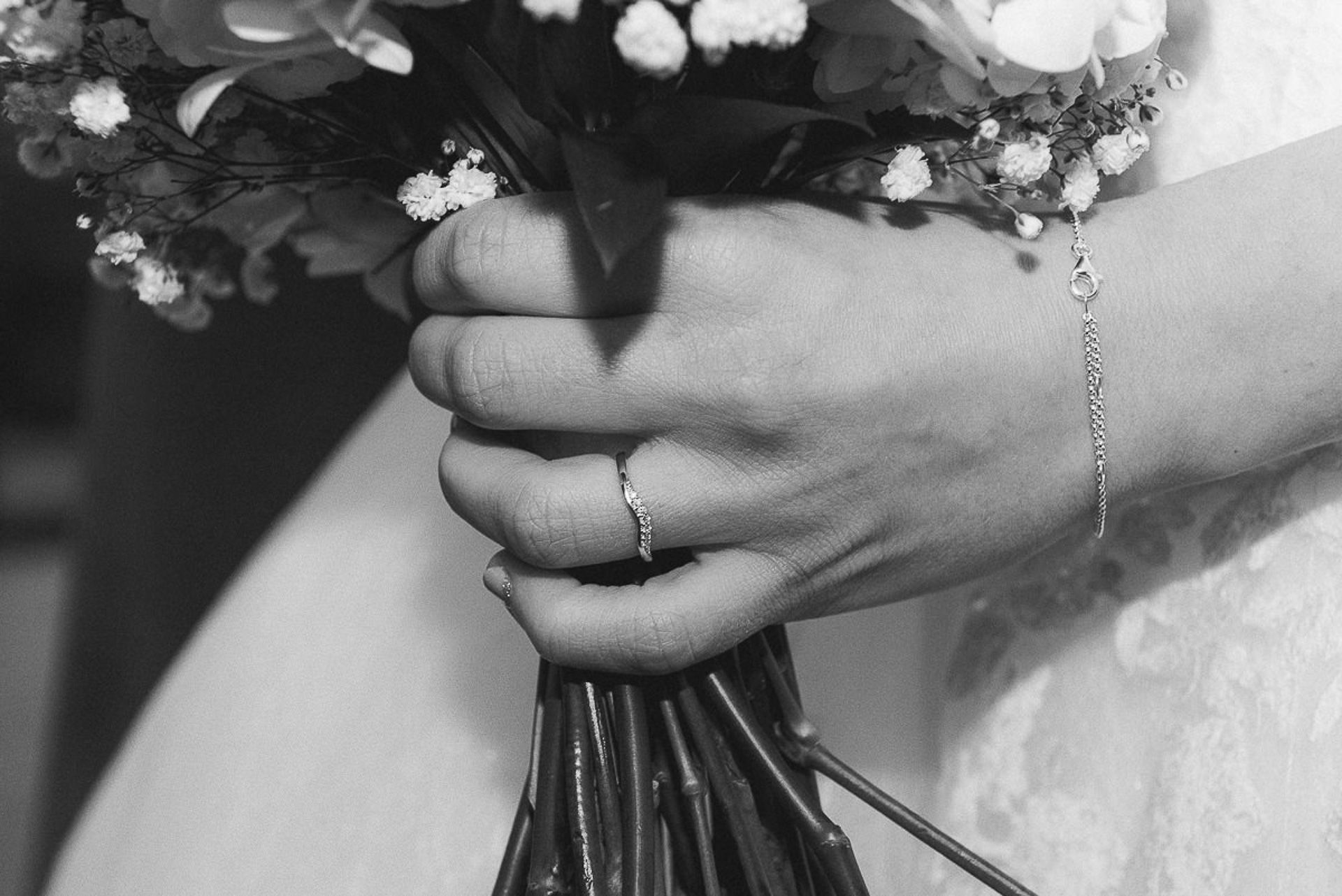 black and white photo of the brides wedding ring as she holds her flowers