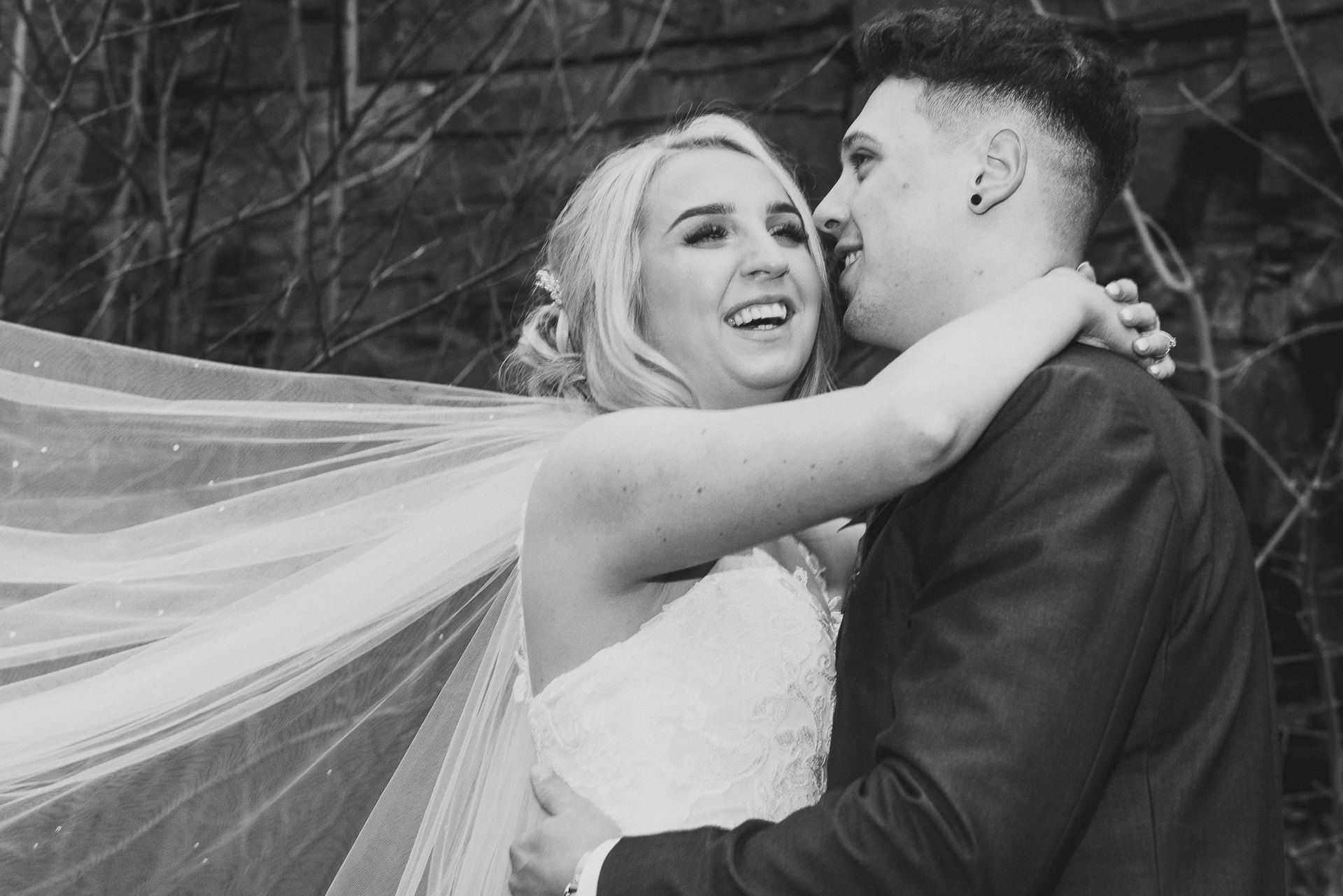 bride laughs as her veil blows in the wind