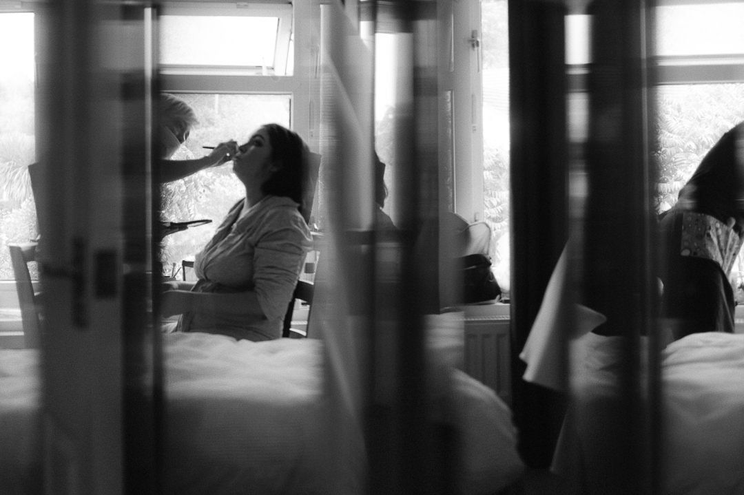 black and white creative image of the bride getting her make up on