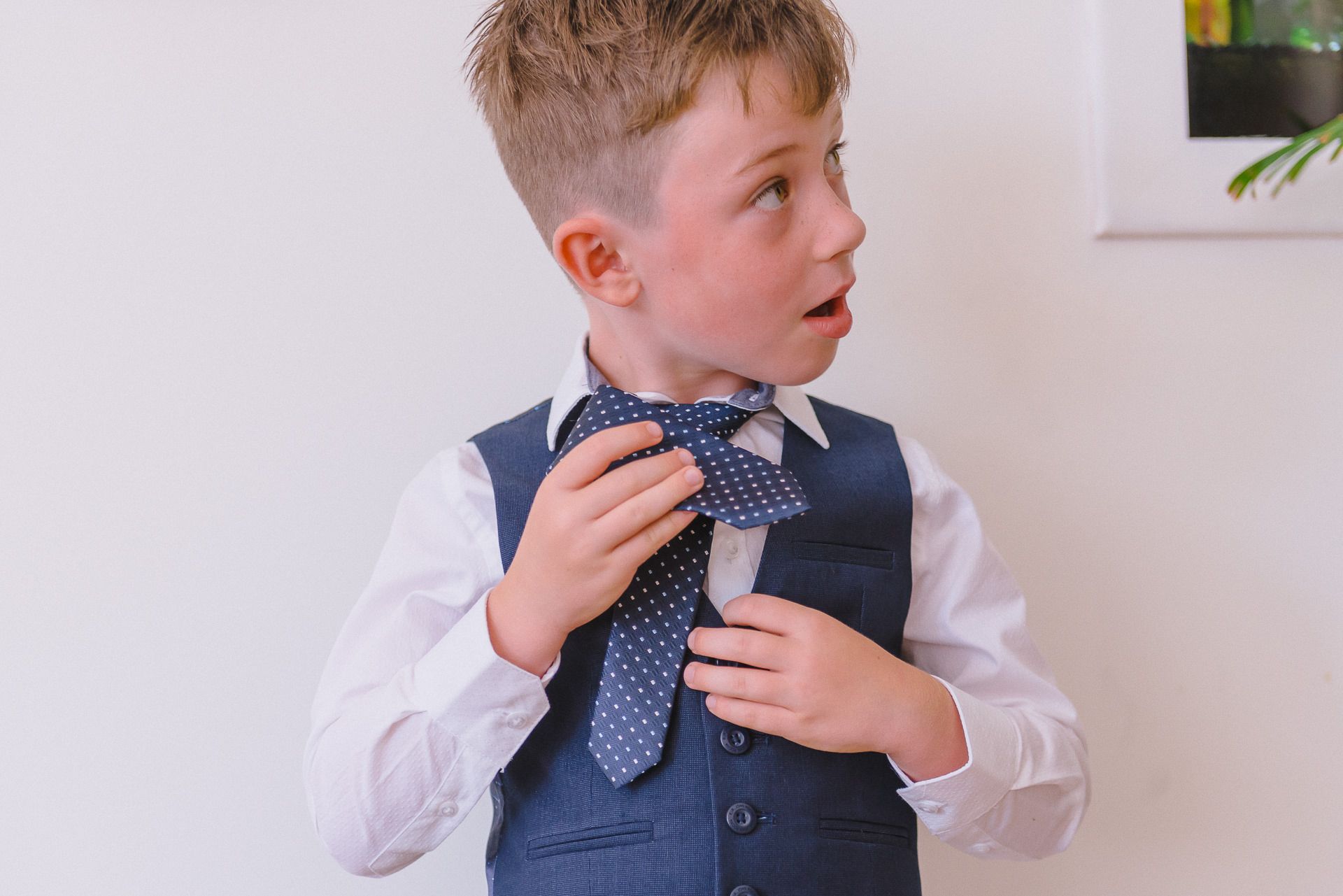 a young page boy is attempting to tie his tie