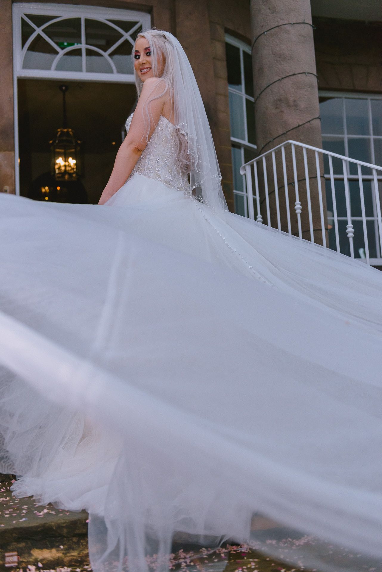 the bride turns to face the camera as she twirls her dress on the venue steps