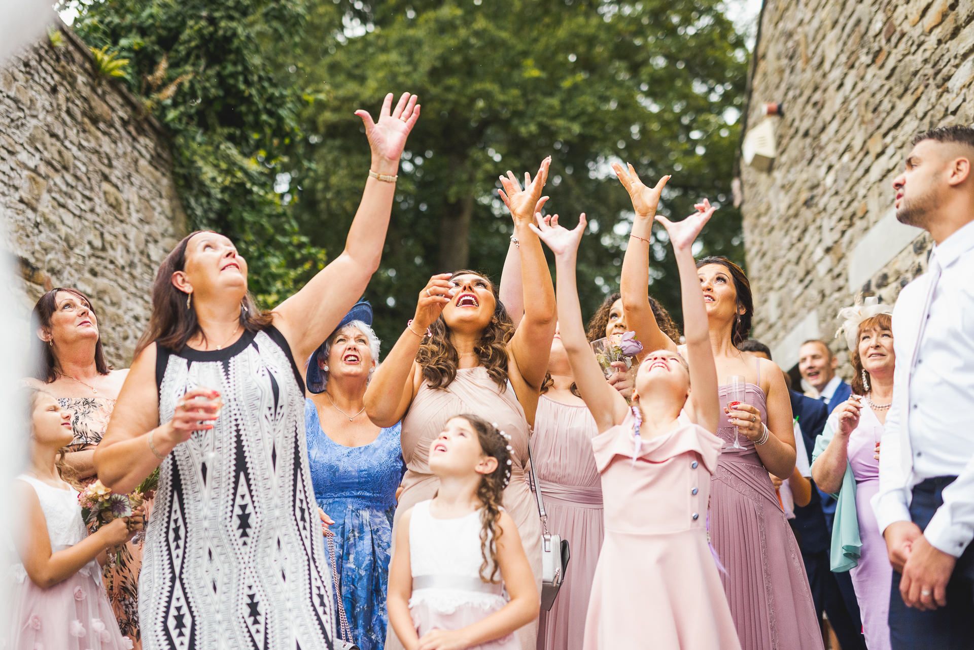 the bridesmaids raise their arms to catch the brides bouquet