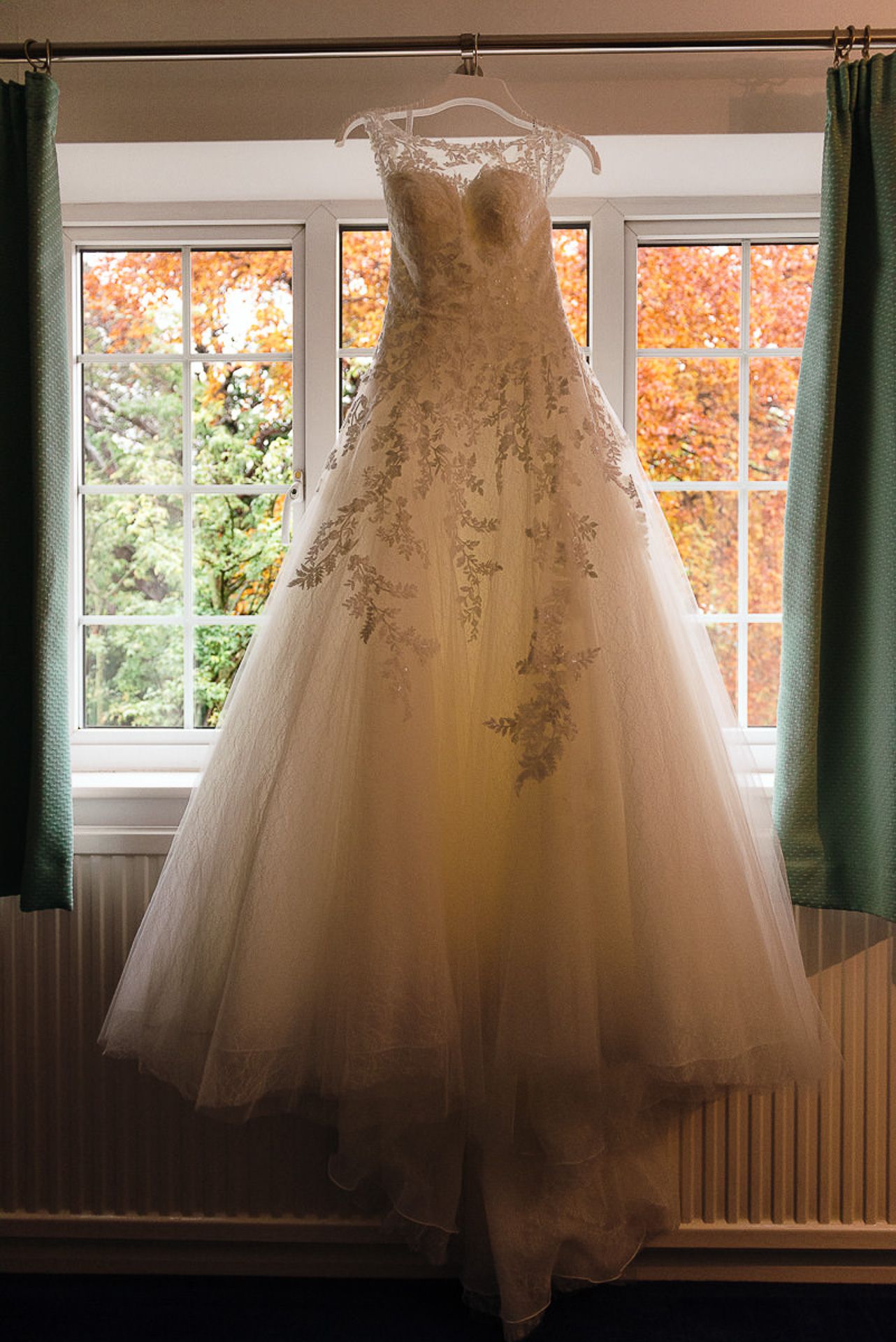 brides wedding dress hangs in the window